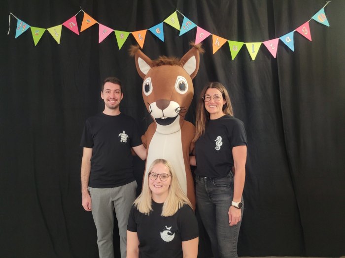 Drei Erwachsene neben dem Maskottchen der Silcherschule